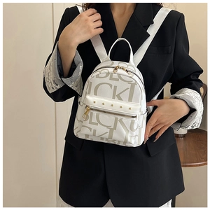 Detail of white PU leather backpack with letter prints and gold rivets on a model