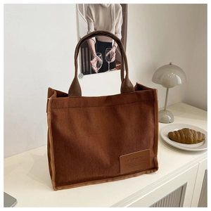 Close-up of brown corduroy tote bag texture with leather patch and woven straps