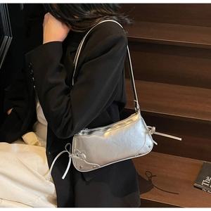 Dettaglio borsa metallizzata argento con texture stropicciata lucida e lacci a fiocco chic