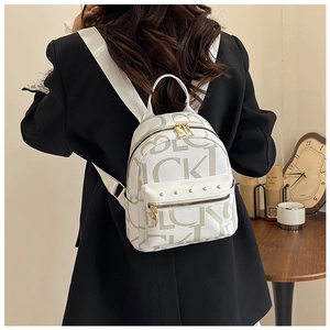 Detail of white PU leather mini backpack featuring brown letter prints and gold zippers