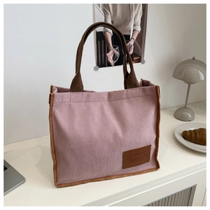 Detailed close-up of pink corduroy tote bag with brown straps and fashion label tag