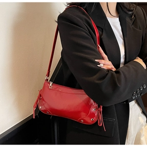Dettaglio borsa sottobraccio in pelle verniciata rossa con zip argento e nappine decorative