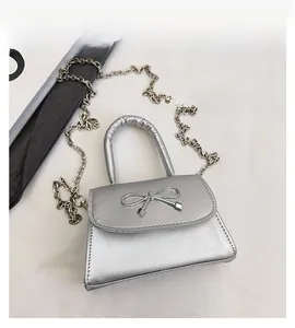 Silver metallic leather mini bag featuring a decorative bow buckle and fine chain strap