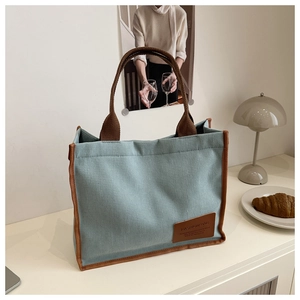 Detailed close-up of light blue corduroy tote bag with brown trim and leather patch