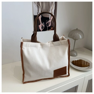 Detail of waffle textured beige tote bag with brown PU leather handle and fashion tag