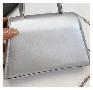 Detail of silver metallic handbag with fine texture and metal chain strap connection