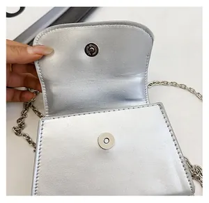 Detail of silver metallic textured handbag showing durable magnetic snap closure and chain