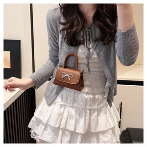 Close-up of retro brown leather mini bag with silver metal bow and fine chain strap