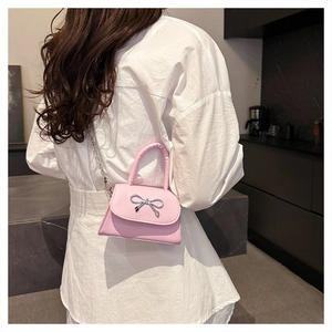 Detail of pink mini handbag with silver bow ornament and detachable metal chain strap