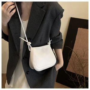 Detail of white PU leather saddle bag with Fashion & Bags print and knotted strap design