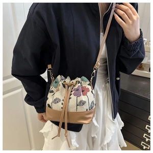 Ethnic style bucket bag with floral tapestry and brown leather strap on model