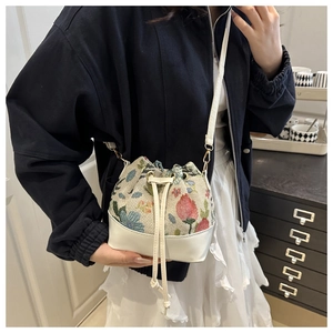 Detailed shot of ethnic floral embroidery pattern on drawstring bucket bag with leather base