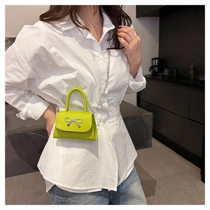 Detail of lime green mini crossbody bag featuring a silver bow buckle and chain strap
