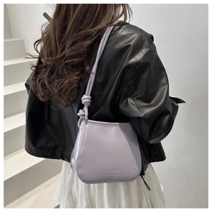 Detail of lavender bucket bag featuring stylish knotted strap and glossy leather finish