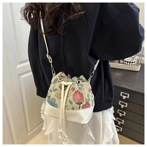 Close-up of the drawstring bucket bag featuring floral fabric and white leather trim