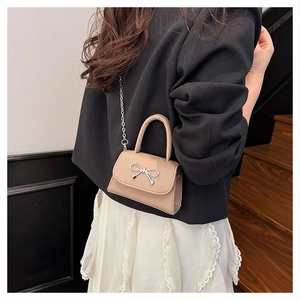 Chic beige mini square bag with silver bow detail and chain strap worn by model