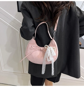 Pink crescent shoulder bag with bow and pearl lace pendant on black suit jacket