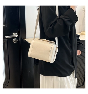 Close-up of cream leather crossbody bag with lychee grain texture and gold metal buckle