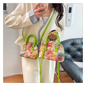 Detail of floral embroidery and cartoon elephant on a cream mini shell bag with green handles