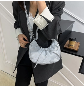 Détail du sac demi-lune argenté avec nœud élégant et boucle métallique ajustable