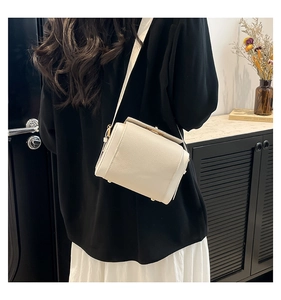 Detailed back view of a cream lychee grain crossbody box bag on a model side