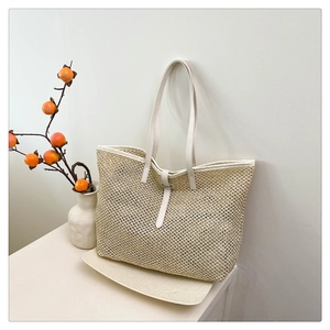 Detailed view of cream woven tote bag with leather straps and delicate openwork pattern