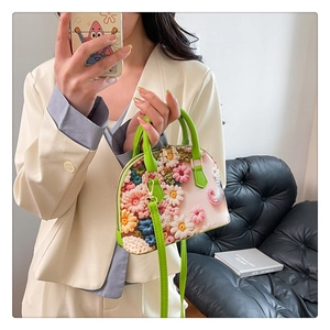 Detailed close-up of colorful 3D floral embroidery and green handles on a pink tote bag