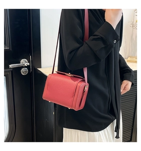 Detail of red pebbled leather box bag worn as a crossbody with adjustable shoulder strap