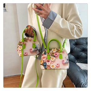 Detailed shot of floral crochet handbag with 3D elephant accent and green straps
