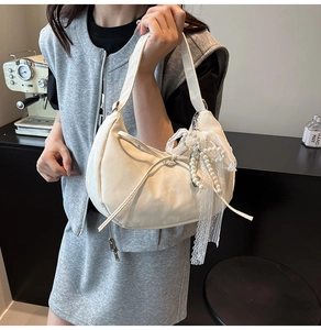 Chic cream dumpling bag with pearl lace pendant shown in a modern lifestyle setting