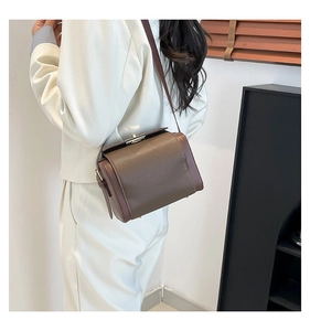 Detail of two-tone brown box bag with metallic clasp worn with a white blazer