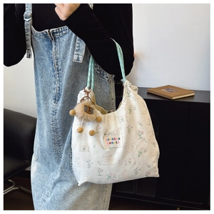 Detail of canvas tote bag with rabbit and tulip print featuring a plaid shoulder strap