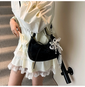Detail of a black velvet crescent bag featuring pearl and lace bow charm with drawstring