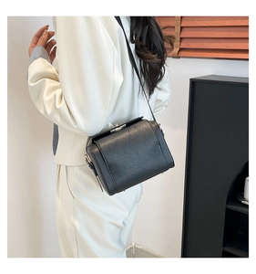 Detail of classic black square bag showing high-quality pebbled leather texture and metal lock