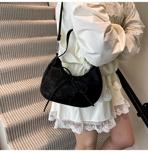 Detail showing soft black velvet texture and bow decoration on the half-moon bag