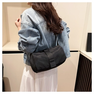 Detail of black nylon crossbody bag featuring wide webbing strap and plastic buckle