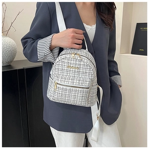 Détail du sac à dos en tweed noir et blanc avec fermetures dorées et bretelles blanches