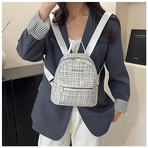 Détail d'un mini sac à dos en tweed noir et blanc avec logo doré sur mannequin