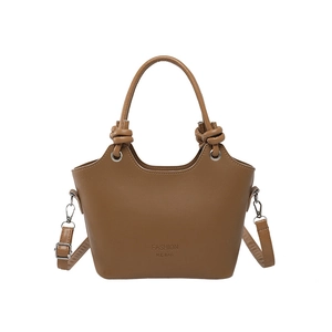 Brown leather bucket bag with knotted handles and adjustable strap on white background