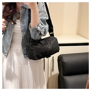 Minimalist black nylon pillow crossbody bag with wide shoulder strap shown on model
