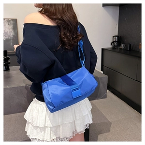 Model wearing a bright blue nylon crossbody bag with adjustable strap and buckle closure