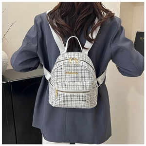 Détail du sac à dos en tweed blanc à carreaux avec zips dorés porté par un mannequin