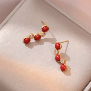 Vintage gold-plated earrings with red zircon inlays on a beige satin background