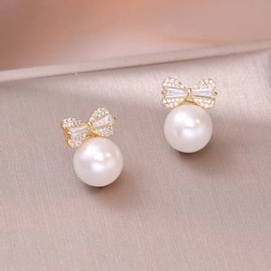 Elegant gold bow earrings with pearls and crystals shown from a 45-degree angle