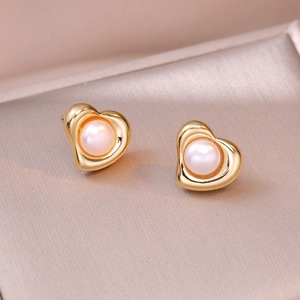 Elegant gold heart earrings with white freshwater pearls shown on a silk textured surface