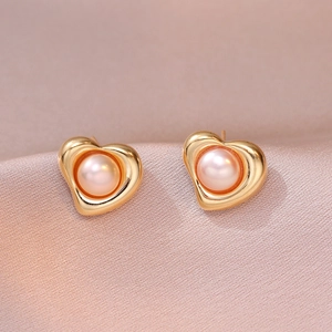 Elegant gold heart earrings with natural freshwater pearls on pink silk background