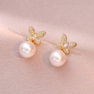 Elegant gold butterfly earrings with sparkling crystals and white round pearls on pink silk
