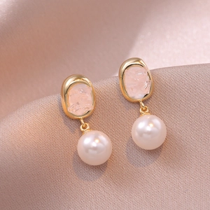 Macro shot of vintage pink crystal and pearl drop earrings on champagne silk background