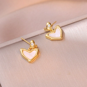 Close-up of pink heart-shaped earrings with gold plating and zircon studs on satin