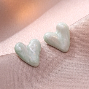 Elegant heart stud earrings in light green marble finish on luxury silk fabric